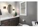 Modern half-bathroom featuring sleek vanity, stylish mirror, contemporary lighting and gray paint at 2656 E Oriole Dr, Gilbert, AZ 85297