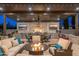 Covered outdoor kitchen area with built-in grill, TV, dining table, and comfortable seating surrounding a cozy fire pit at 2656 E Oriole Dr, Gilbert, AZ 85297