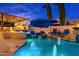 Inviting pool with a built-in fire pit, outdoor kitchen, lounge chairs under umbrellas, and tall trees at 2656 E Oriole Dr, Gilbert, AZ 85297