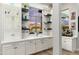 Stylish wet bar with white cabinets, open shelving, and a view of the outdoor landscape at 2656 E Oriole Dr, Gilbert, AZ 85297