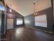 Open living room features hardwood floors, neutral paint, two chandeliers, and two windows at 3229 S 93Rd Ave, Tolleson, AZ 85353