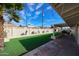 View of the backyard from under a palm tree, including the synthetic lawn and covered patio at 3716 W Griswold Rd, Phoenix, AZ 85051