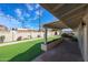 View of the backyard with the synthetic lawn, including the block wall and covered patio at 3716 W Griswold Rd, Phoenix, AZ 85051