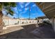 View of the backyard from under a palm tree, including the block wall and covered patio at 3716 W Griswold Rd, Phoenix, AZ 85051