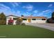 Charming single-story home features a vibrant yellow door and manicured landscaping, complete with a large driveway at 3716 W Griswold Rd, Phoenix, AZ 85051