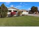 Single story home features manicured landscaping, with bright bushes and mature trees in the front yard at 3716 W Griswold Rd, Phoenix, AZ 85051