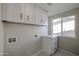 Bright laundry room with white cabinets, drawers, countertop, and a window at 3716 W Griswold Rd, Phoenix, AZ 85051