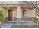Covered front porch with stone accents, a brown front door, and side panel window at 37292 N Yellowstone Dr, San Tan Valley, AZ 85140