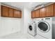 Functional laundry room with matching washer and dryer, upper cabinets and white tile flooring at 37292 N Yellowstone Dr, San Tan Valley, AZ 85140