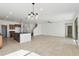 Bright open-concept living space boasts a kitchen island, neutral tile flooring, and access to staircase at 37292 N Yellowstone Dr, San Tan Valley, AZ 85140