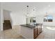 Open-concept living space with neutral tile flooring, a kitchen island, and a staircase to the second floor at 37292 N Yellowstone Dr, San Tan Valley, AZ 85140