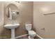 Cozy half-bathroom with pedestal sink, round mirror, and neutral color palette at 42735 W Bravo Dr, Maricopa, AZ 85138