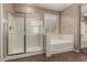 Bathroom featuring a glass-enclosed shower and a soaking tub by the window at 42735 W Bravo Dr, Maricopa, AZ 85138