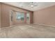 Spacious bedroom with plush carpeting, bay windows, and a modern ceiling fan at 42735 W Bravo Dr, Maricopa, AZ 85138