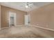 Neutral bedroom features carpet flooring, ceiling fan, and access to an ensuite bathroom and walk-in closet at 42735 W Bravo Dr, Maricopa, AZ 85138