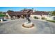 Clubhouse entrance featuring bronze horse statue on a roundabout with landscaped flower beds at 42735 W Bravo Dr, Maricopa, AZ 85138