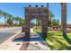 Grand stone entrance to 'Rancho El Dorado' with palm trees lining the street, showcasing a welcoming community at 42735 W Bravo Dr, Maricopa, AZ 85138