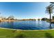 Picturesque view of the lake featuring multiple fountains in a community with beautiful landscaping and clear skies at 42735 W Bravo Dr, Maricopa, AZ 85138