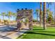 Stone monument sign at Rancho El Dorado entrance with mature landscaping and palm trees under a clear blue sky at 42735 W Bravo Dr, Maricopa, AZ 85138