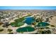 Aerial view of a golf course with three ponds, lush landscaping, and community homes in the background at 42735 W Bravo Dr, Maricopa, AZ 85138