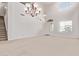 Bright living room with a soaring ceiling, plush carpeting, and an elegant chandelier at 42735 W Bravo Dr, Maricopa, AZ 85138