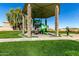 Community playground featuring a covered play structure with slides and climbing features on a well-maintained green lawn at 42735 W Bravo Dr, Maricopa, AZ 85138