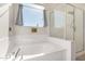 Bright bathroom featuring a soaking tub, glass-enclosed shower, and a sunny window at 5345 W Leodra Ln, Laveen, AZ 85339