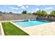 Sparkling pool with water feature, stone surround, and artificial turf, perfect for relaxation and outdoor enjoyment at 5345 W Leodra Ln, Laveen, AZ 85339