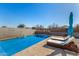 Backyard pool with lounge chairs, an umbrella, and desert landscaping at 5345 W Leodra Ln, Laveen, AZ 85339