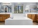 Bathroom with a large soaking tub, wood cabinets, and a window providing natural light at 5422 W Bryce Ln, Glendale, AZ 85301