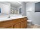 Bathroom features a vanity, mirror, toilet, and shower with a decorative shower curtain at 5422 W Bryce Ln, Glendale, AZ 85301