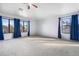 Bright bedroom featuring plush carpeting, a ceiling fan, and large windows with blue curtains at 5422 W Bryce Ln, Glendale, AZ 85301