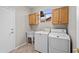Functional laundry room with tile floors, utility sink, washer, dryer, and wooden cabinets at 6353 S Eagle Ct, Gold Canyon, AZ 85118