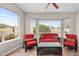 Relaxing sunroom with large windows, tile floors, and comfortable red sofas and chairs at 6353 S Eagle Ct, Gold Canyon, AZ 85118