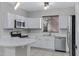 Bright kitchen featuring stainless steel appliances, white cabinetry, and a breakfast bar with quartz countertops at 681 E Los Arboles Pl, Chandler, AZ 85225