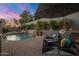 Backyard pool area featuring a stone water feature, lounge chairs, lush plants, and privacy wall at 9412 E Hidden Spur Trl, Scottsdale, AZ 85255
