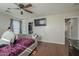 Comfortable bedroom featuring wood-look flooring, a ceiling fan, and a wall-mounted television at 10423 W Hughes Dr, Tolleson, AZ 85353