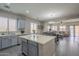 Open concept kitchen with gray cabinets and a view into dining and living areas at 10423 W Hughes Dr, Tolleson, AZ 85353