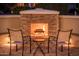 Cozy stone fireplace at dusk with seating, creating a warm and inviting outdoor ambiance at 12936 W Sola Dr, Sun City West, AZ 85375