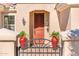 Charming front entrance featuring a wooden door, decorative sconces, and vibrant potted plants at 12936 W Sola Dr, Sun City West, AZ 85375