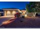 Charming home with a large garage, desert landscaping, and warm lighting at dusk at 12936 W Sola Dr, Sun City West, AZ 85375