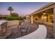 Beautiful outdoor living space with a cozy fireplace, dining set, and lush landscaping at 12936 W Sola Dr, Sun City West, AZ 85375