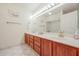 Well-lit bathroom featuring dual sinks, wood cabinets, and a large mirror for a luxurious experience at 13232 W Ballad Dr, Sun City West, AZ 85375