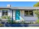 Home's entrance with a vibrant blue door, white exterior, and manicured garden at 13446 N 18Th Ave, Phoenix, AZ 85029