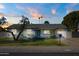 Charming single-story home with a vibrant blue door, well-manicured lawn, and mature landscaping at dusk at 13446 N 18Th Ave, Phoenix, AZ 85029