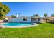 Backyard view of a swimming pool surrounded by green grass with a white house in the background at 13446 N 18Th Ave, Phoenix, AZ 85029