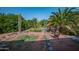 Lush backyard featuring a tall cactus, palm trees, a dining table, and an inviting copper fire pit at 14264 S Baniff Ln, Arizona City, AZ 85123