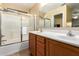 Well-lit bathroom featuring a double sink vanity and a shower with glass doors at 16150 W Hope Dr, Surprise, AZ 85379