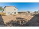 Rear exterior view of a two-story home with a spacious, empty backyard enclosed by a block wall at 16219 W Woodlands Ave, Goodyear, AZ 85338