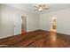 Spacious bedroom with wood-look flooring, ceiling fan, and doorways to other rooms at 16219 W Woodlands Ave, Goodyear, AZ 85338